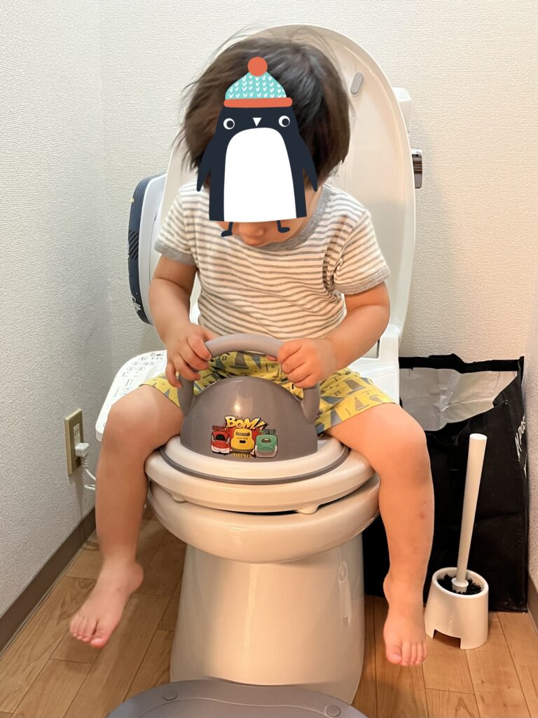 取っ手付き補助便座に座る息子